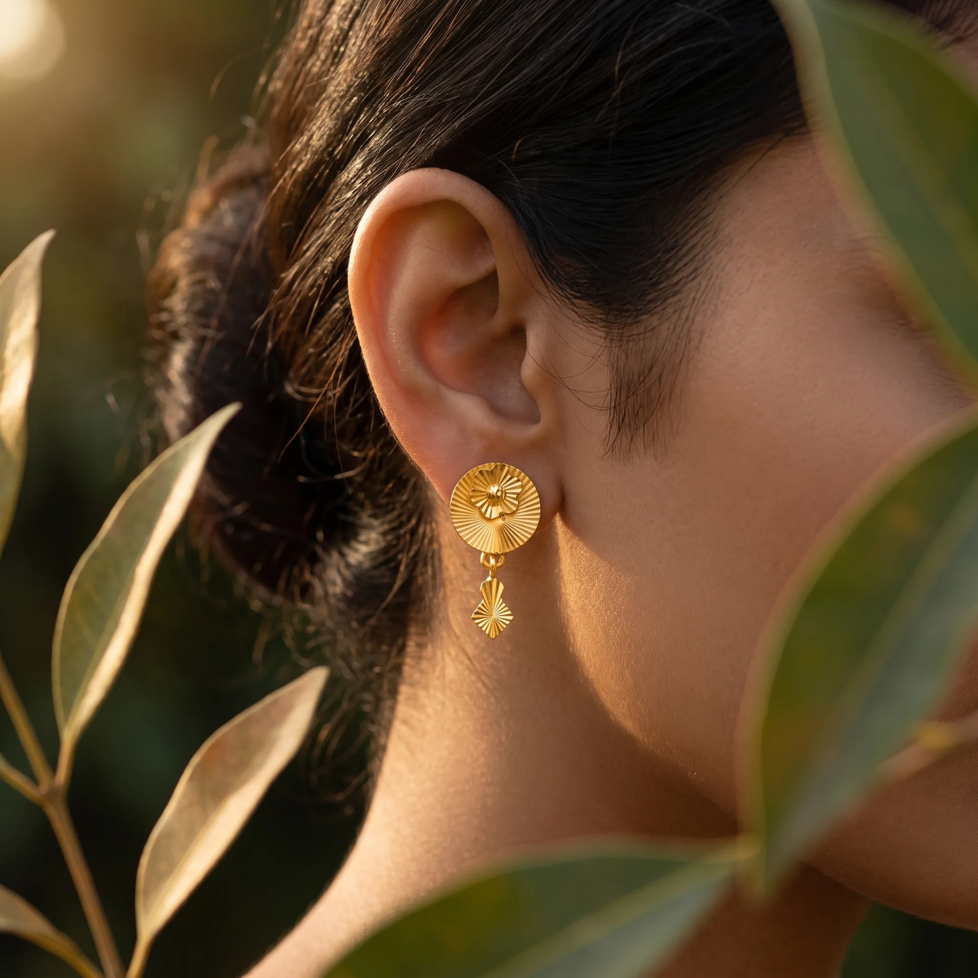 Gold fluted drop earring worn, backlit in golden hour